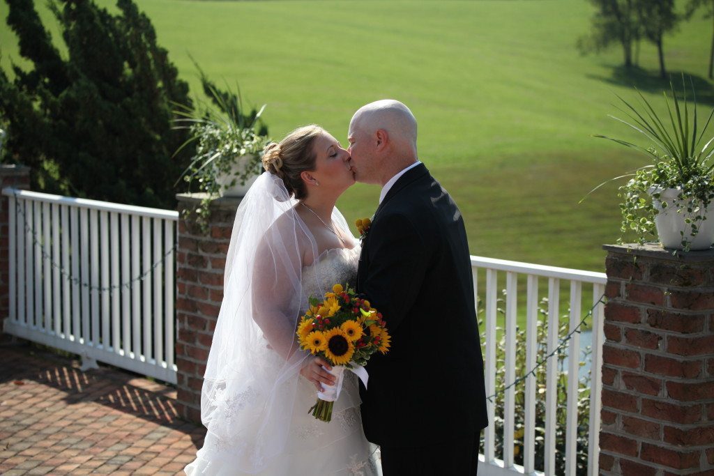 Bride and groom kiss on the patio of Morningside Inn after their summer outdoor wedding ceremony.