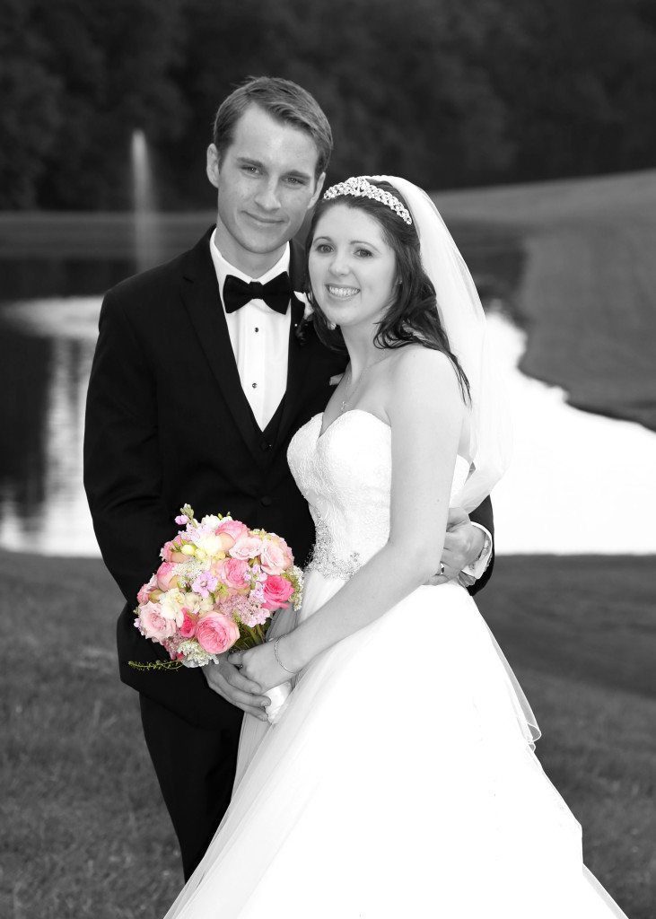 Bride and groom by pond black and white with color flowers
