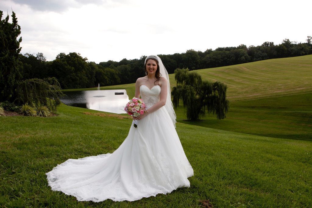 Bride by wedding venue with pond