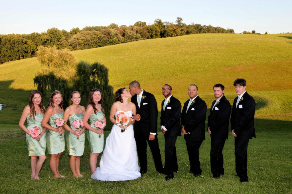 Wedding party on lawn by pond and willow tree
