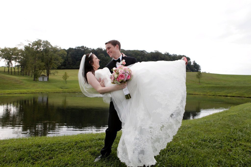 Groom carries bride by pond after wedding at Morningside Inn