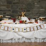 creative wedding favor idea of decorated table of cookies and homemade treats. banner is attached to front of table displaying "love is sweet"