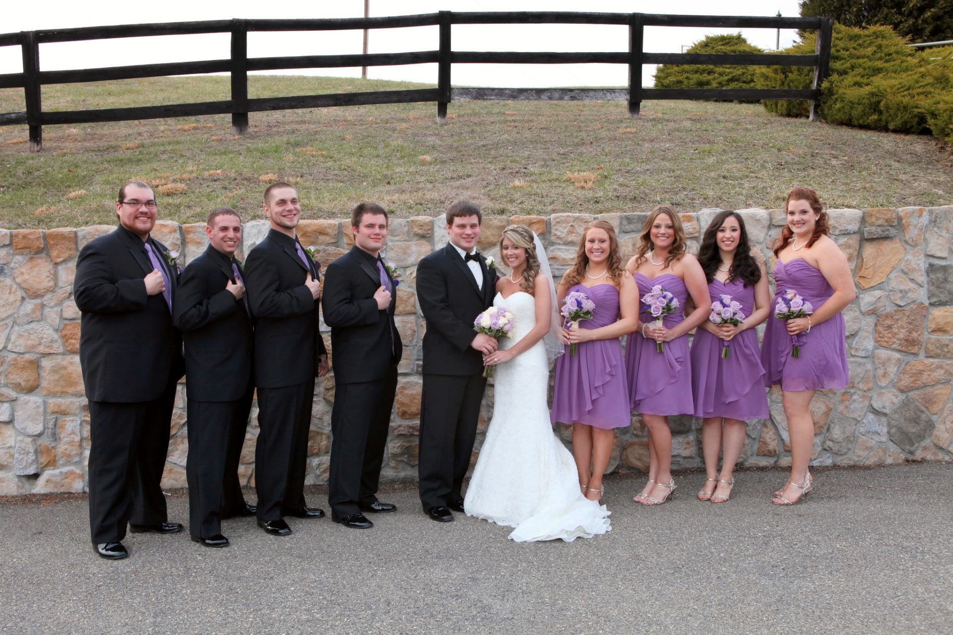 Wedding party pose in front of stone wall