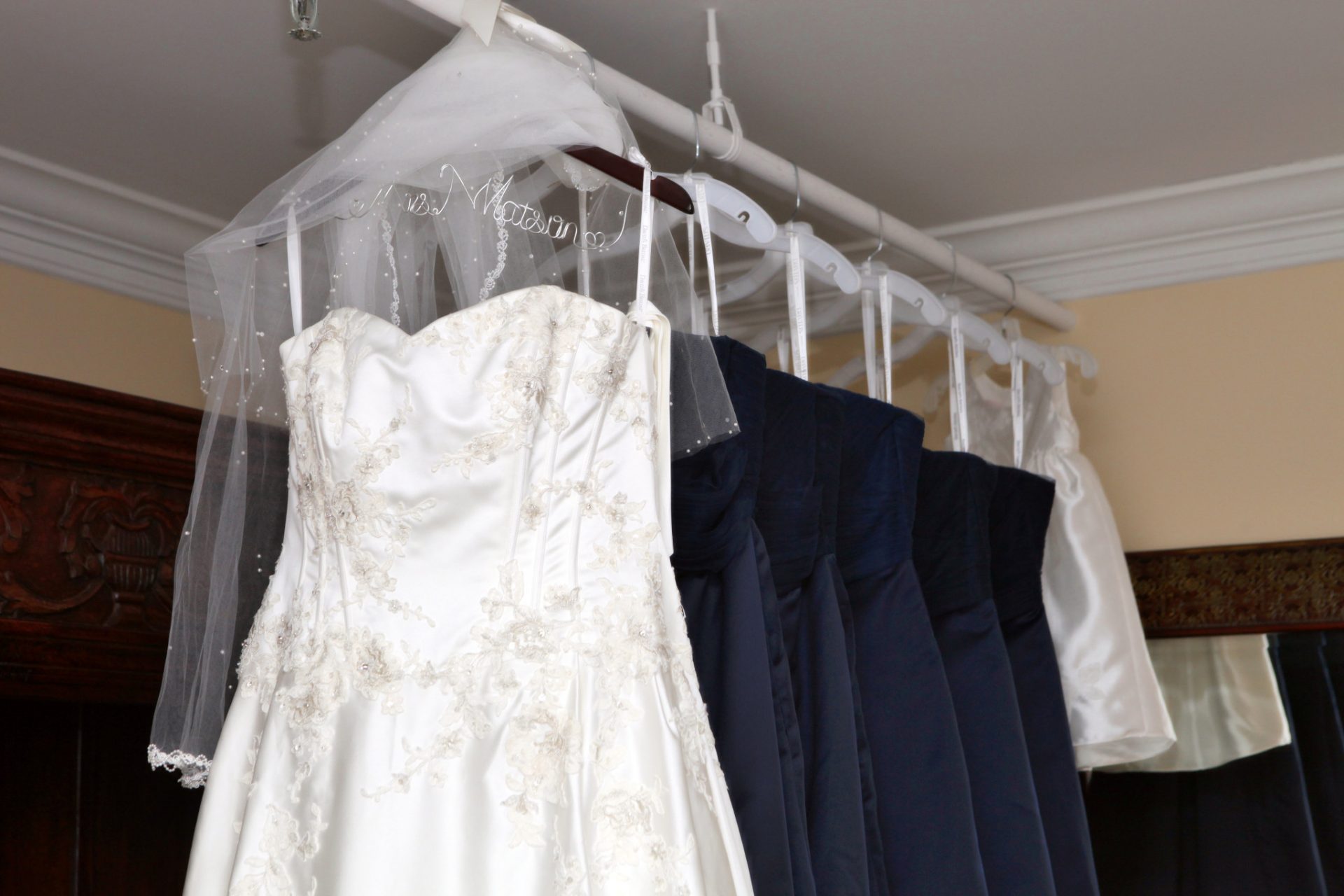 wedding dress and brides' maid dresses all hanging in brides room at morningside inn for this may outdoor wedding