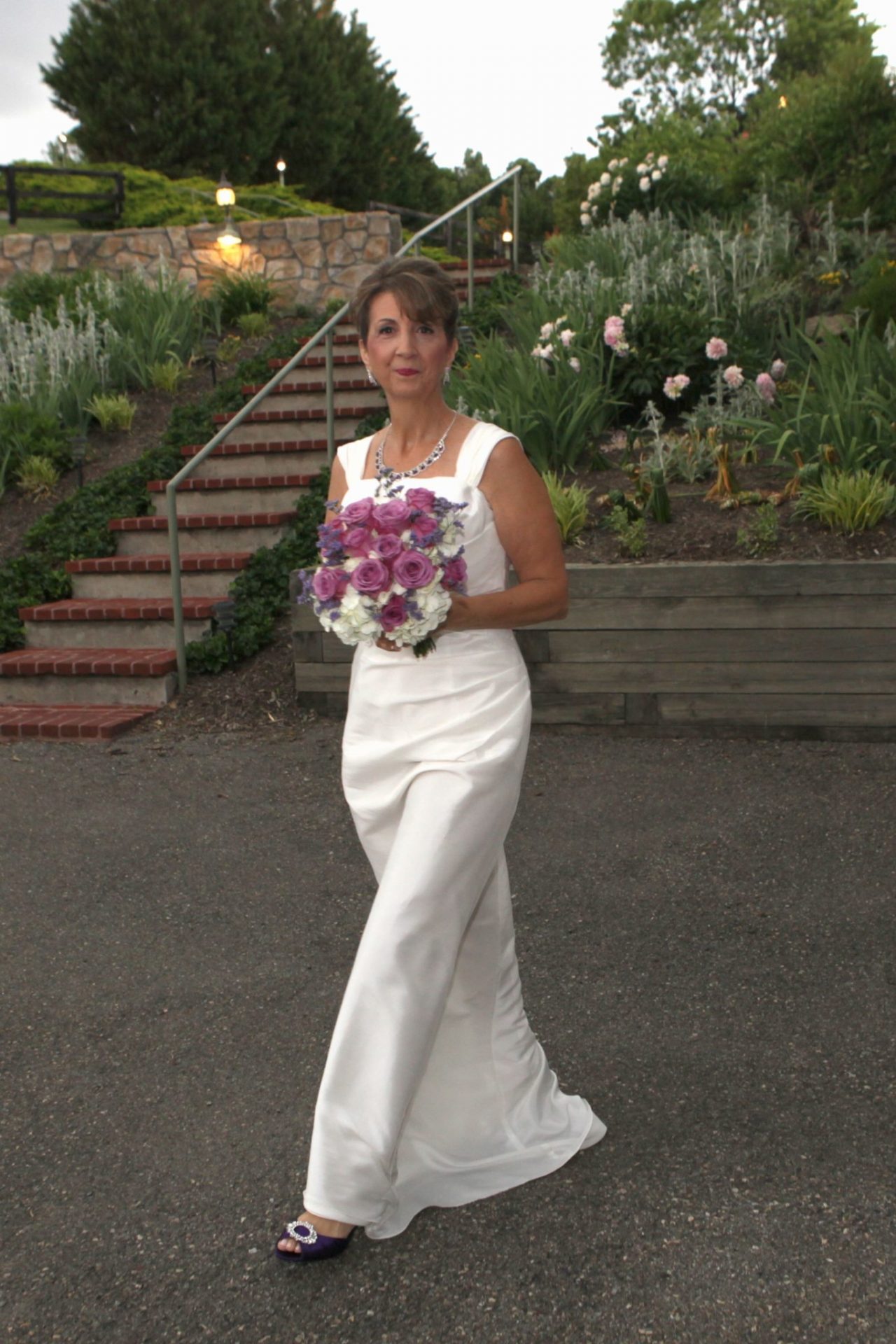 Bride walks from bride's room to the side deck before her wedding ceremony at Morningside Inn, in the background are the brick steps leading to the main entrance of the building.