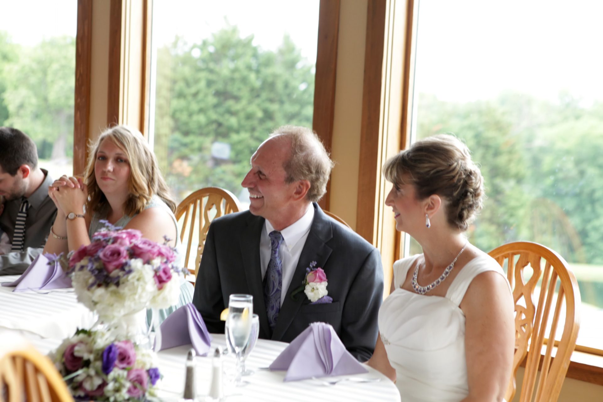 Bride and groom are all smiles during the best man speech as they sit in from of the windows in the main dining room. The dining room is lined with windows for expansive views of the rolling green hills at Morningside Inn.