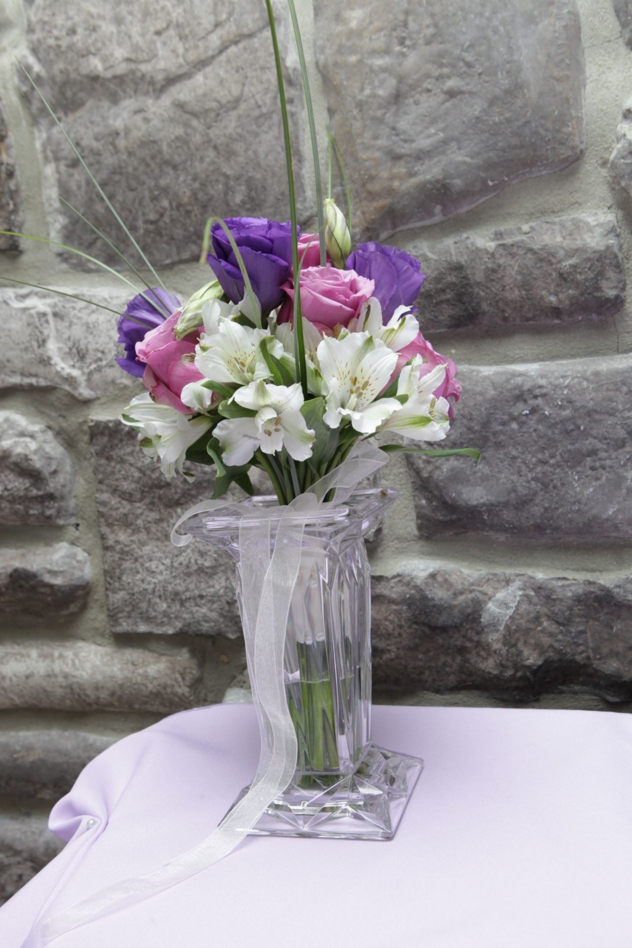 Bride and groom chose pink, purple, and white color scheme as seen in this floral arrangement used as table centerpiece.