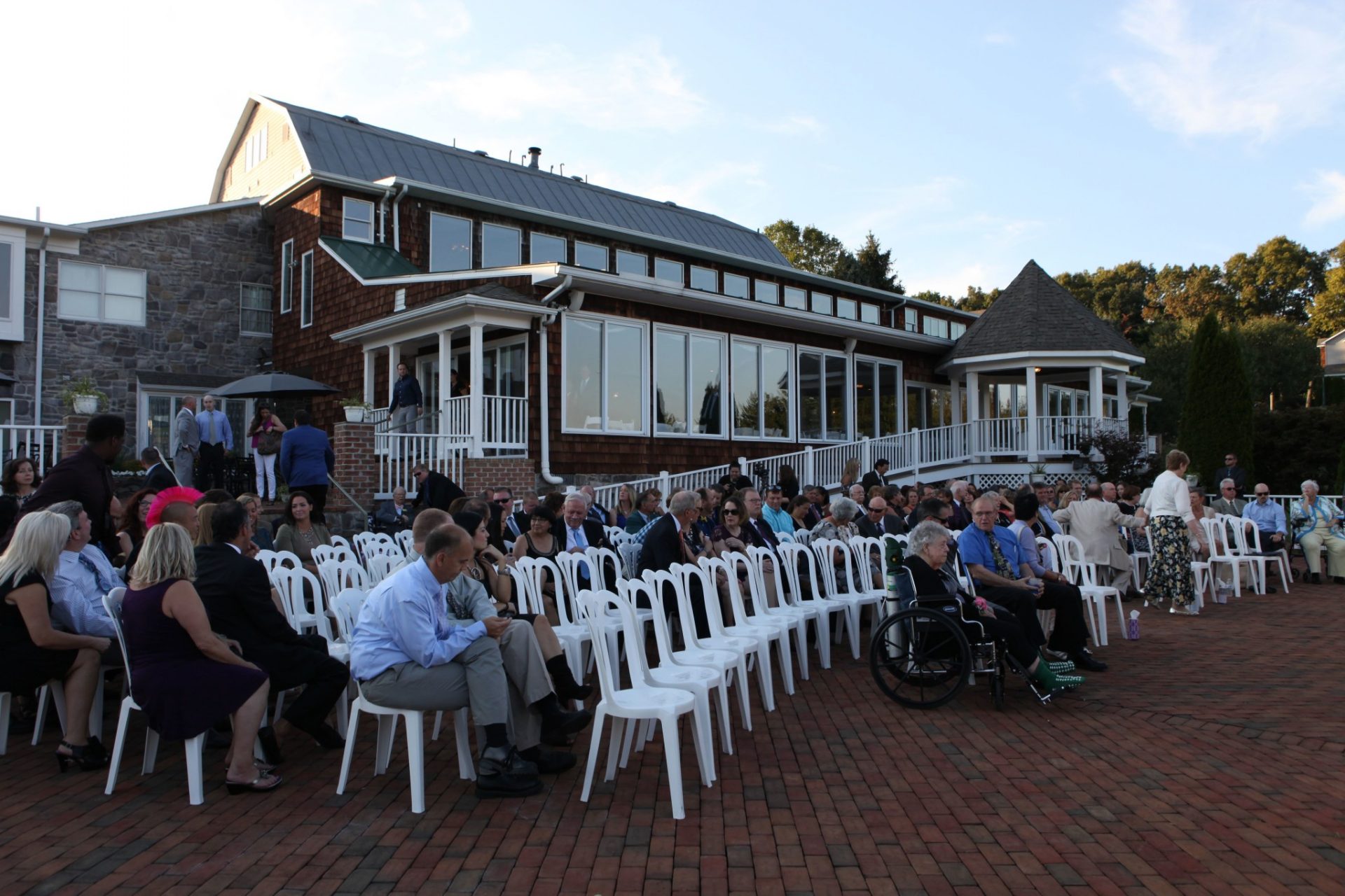 Guests prepare for wedding by taking their seats on the brick patio before wedding