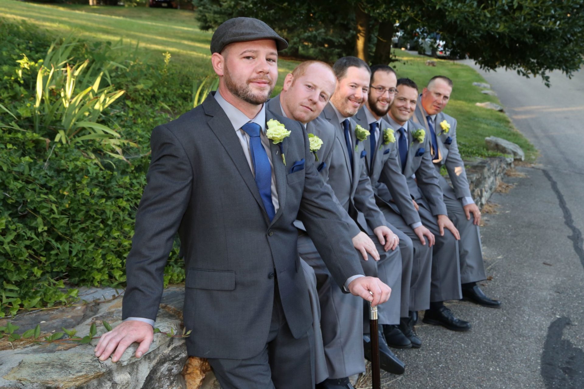 Groom and groom's men line up on stone wall outside of groom's room