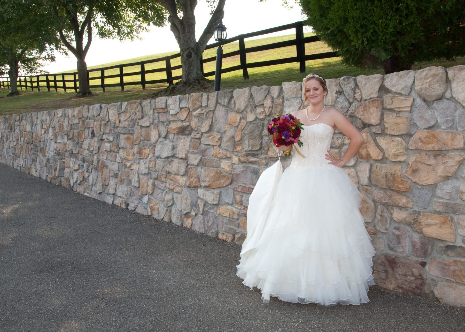 Bride poses by old stone wall at Morningside Inn wedding venue