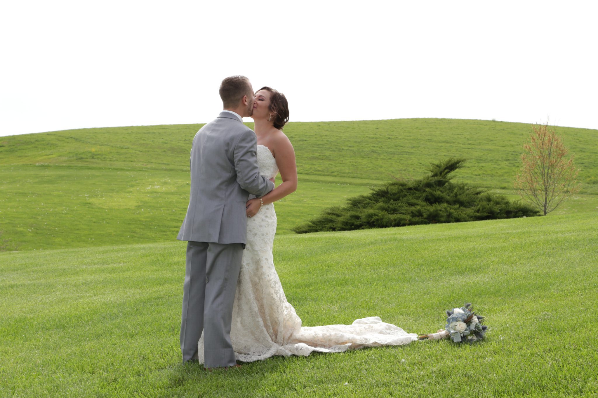 Bride and groom kiss on the lawn after their April country wedding