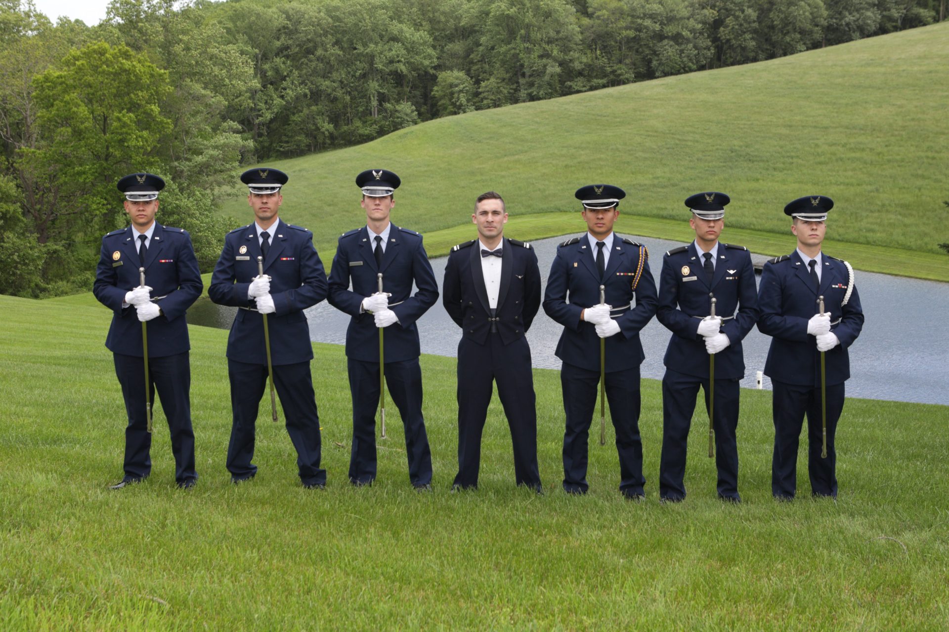Military wedding, groom poses with groomsmen on lawn by pond at Morningside Inn