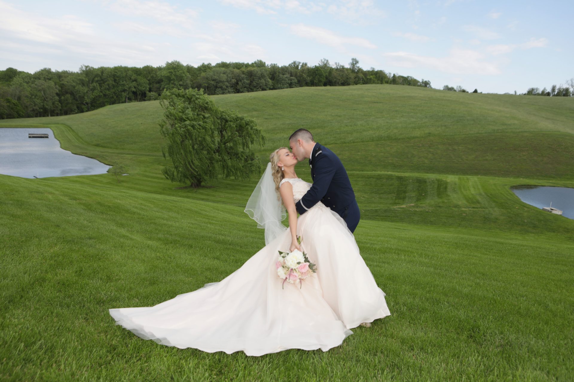 Bride and groom kiss on lawn between two ponds at Morningside Inn