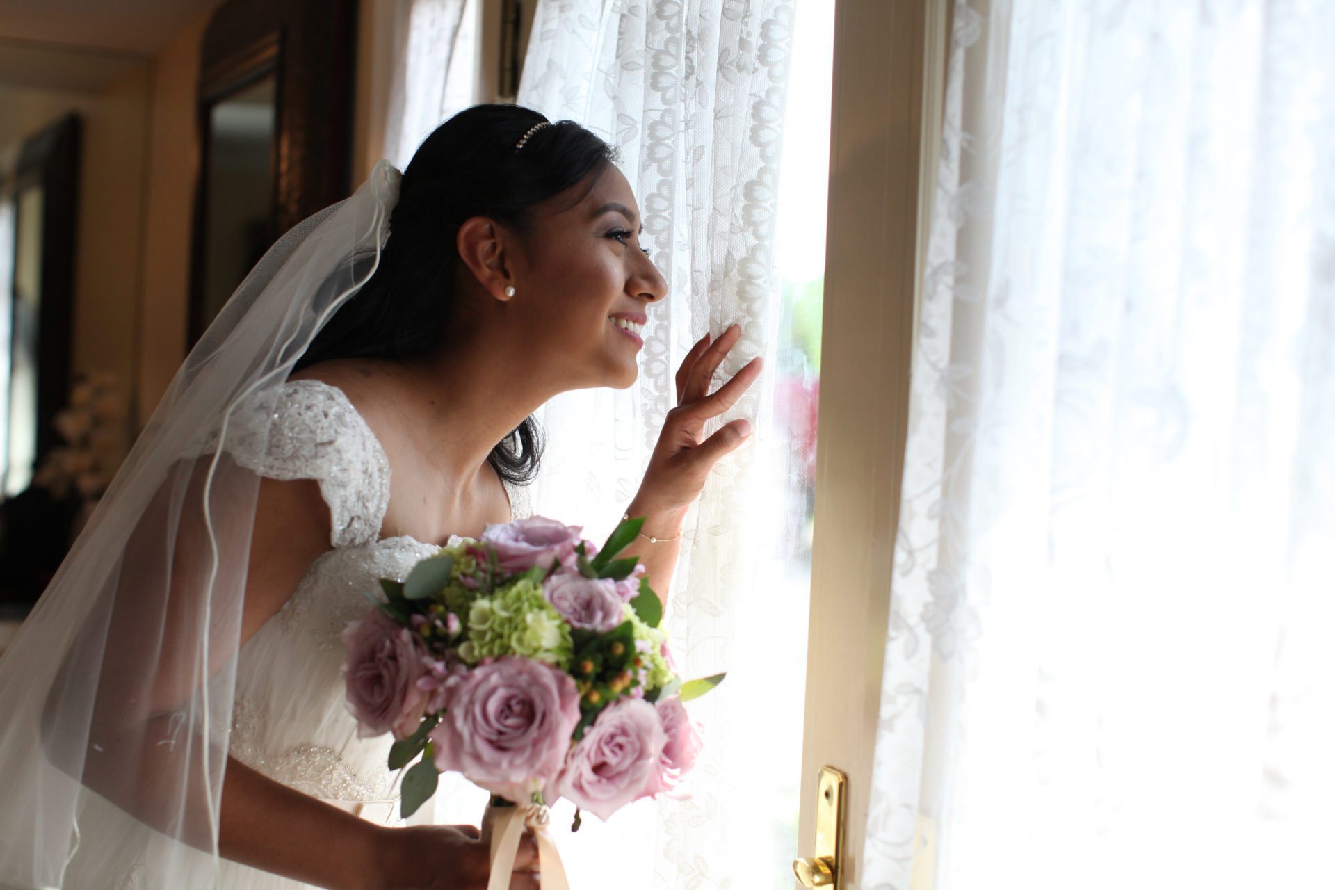 bride looks out window before outdoor wedding ceremony at Morningside Inn