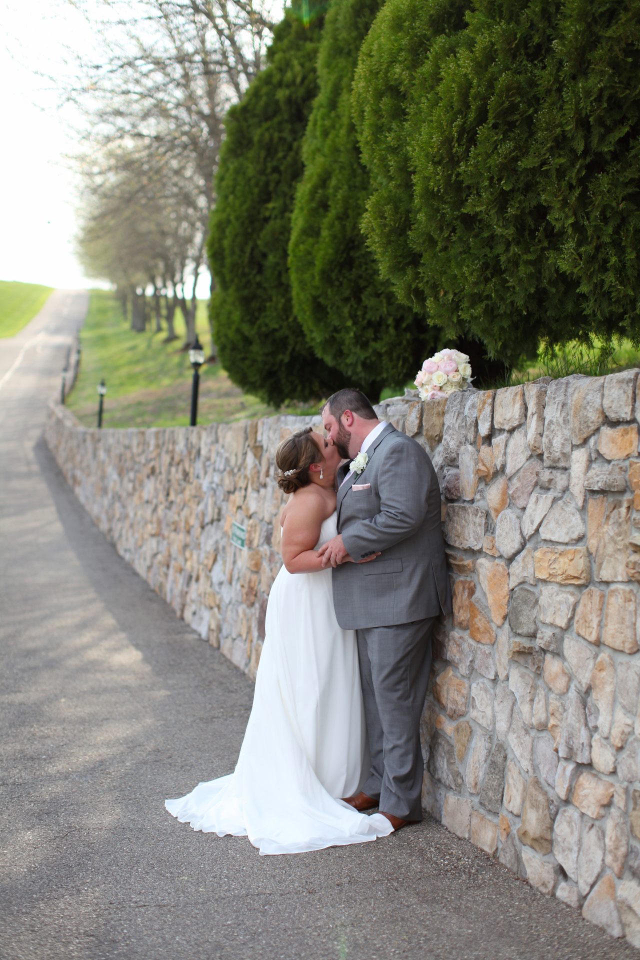 kiss by stone wall Sam & Amy's Wedding April 15 2017