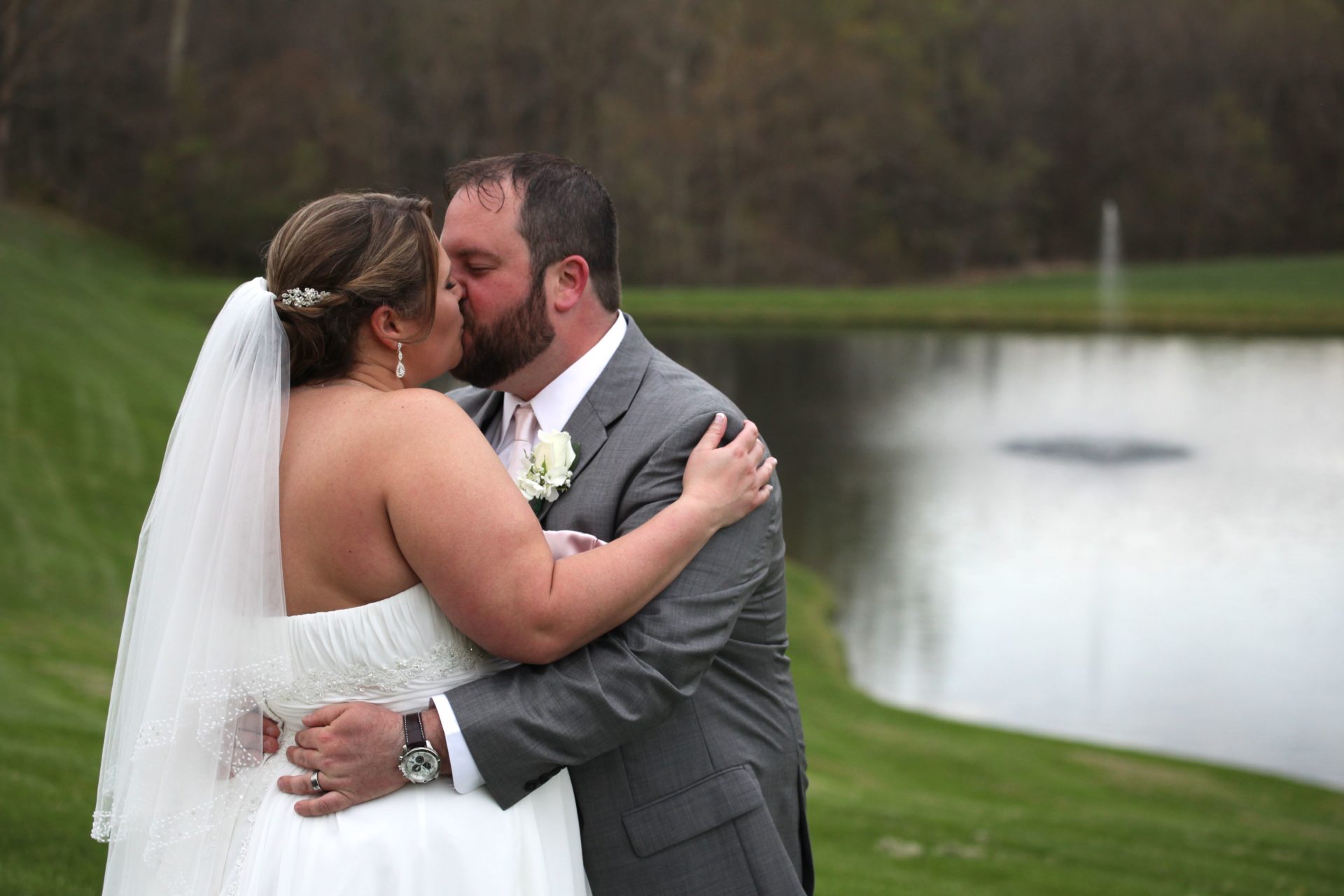 Bride and groom kiss by pond