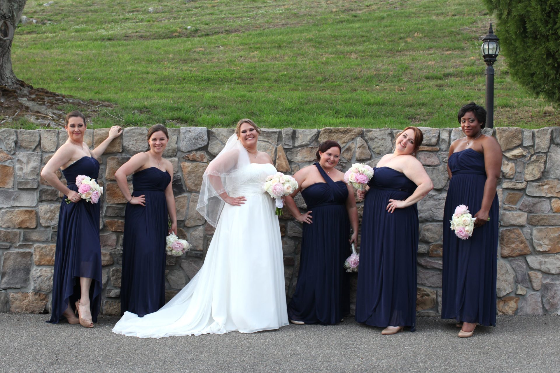 Bridesmaid and bride in front of stone wall