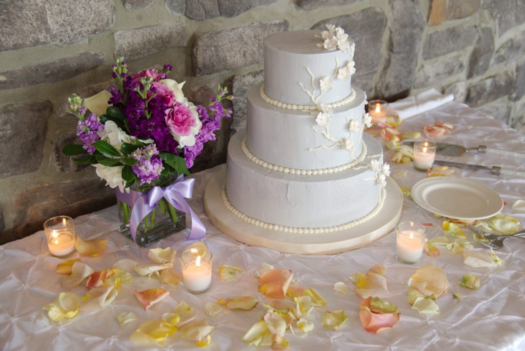 Three tiered wedding cake all white with white flowers.