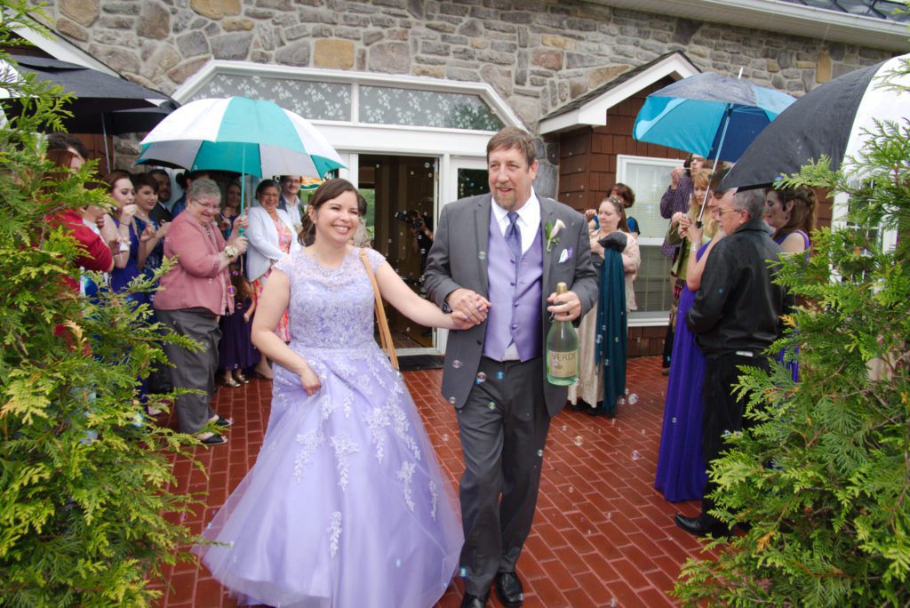 Bride and groom leave Morningside Inn in rain after wedding ceremony.