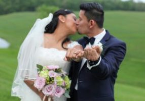 Bride and groom show rings while kissing in back field of Morningside Inn wedding venue in Frederick MD