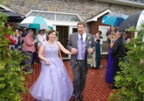 Bride and groom leave Morningside Inn in rain after wedding ceremony.